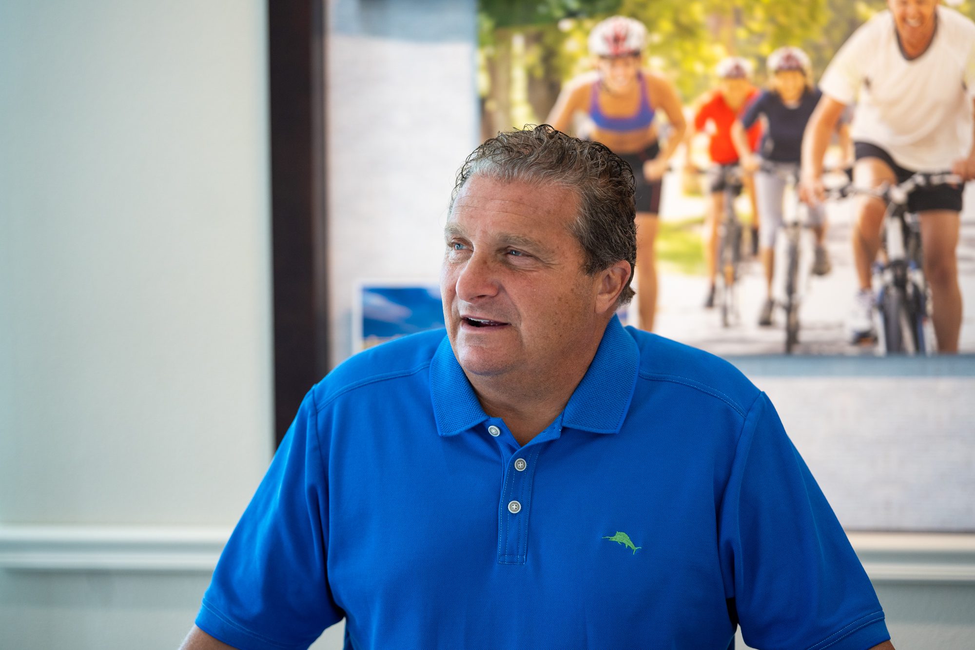 Smiling man in a blue polo shirt indoors.